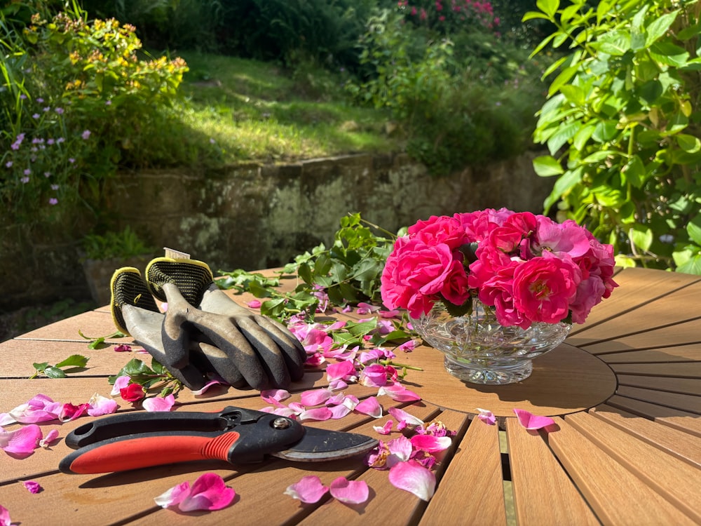 Gartentisch mit Handschuhen, Gartenschere und frisch geschnittenen Rosen