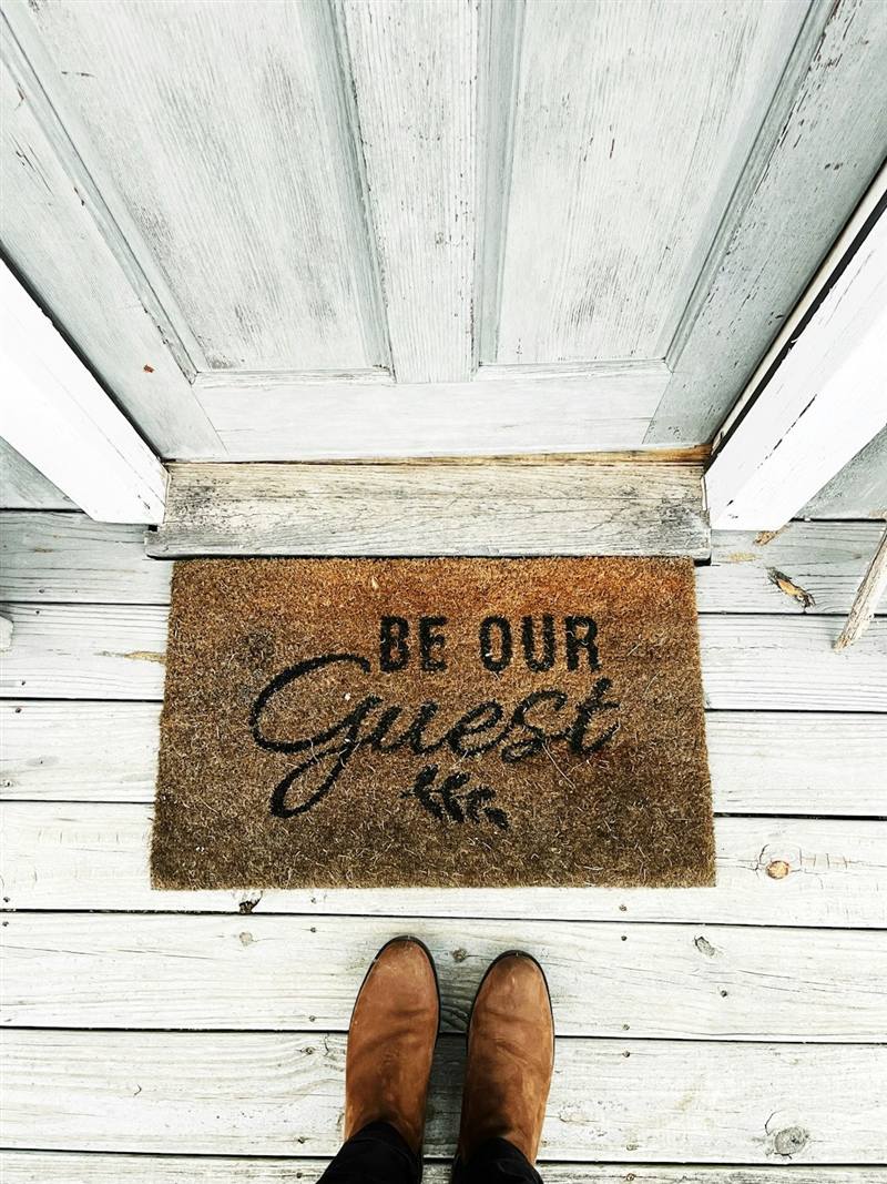 Fußmatte mit der Aufschrift „Be our Guest“ vor der Wohnungstür